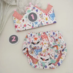 Conjunto corona cumpleaños y cubrepañal unicornios motas coral